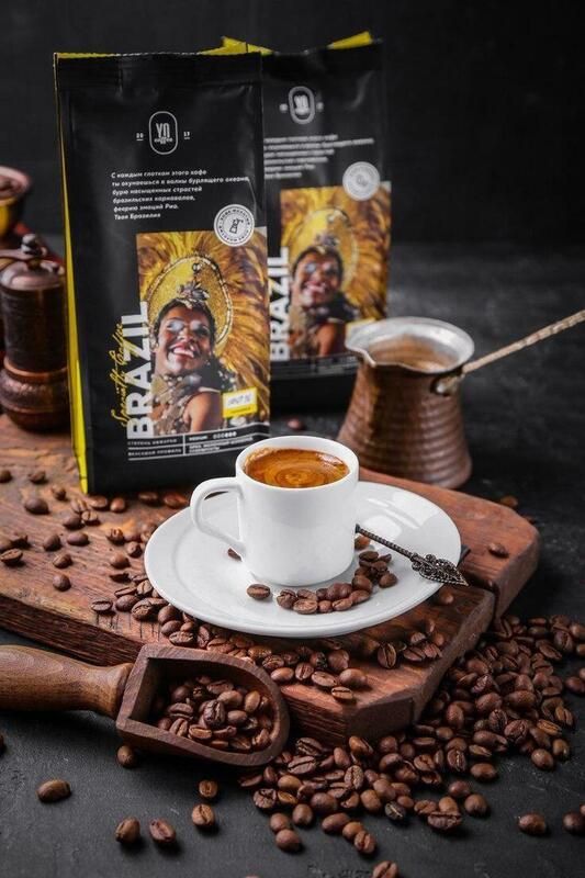 a cup of coffee sitting on top of a wooden cutting board next to some beans