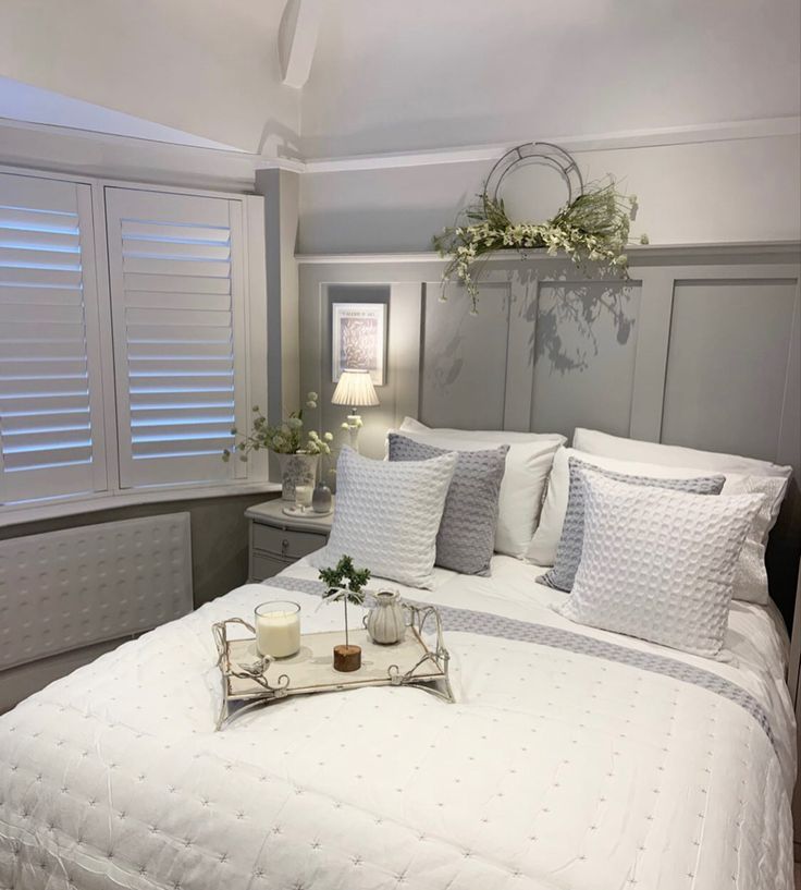 a bed with white sheets and pillows on top of it next to a tray filled with flowers