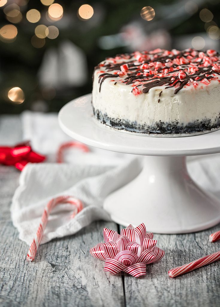 a white cake with chocolate frosting and sprinkles on top, surrounded by candy canes