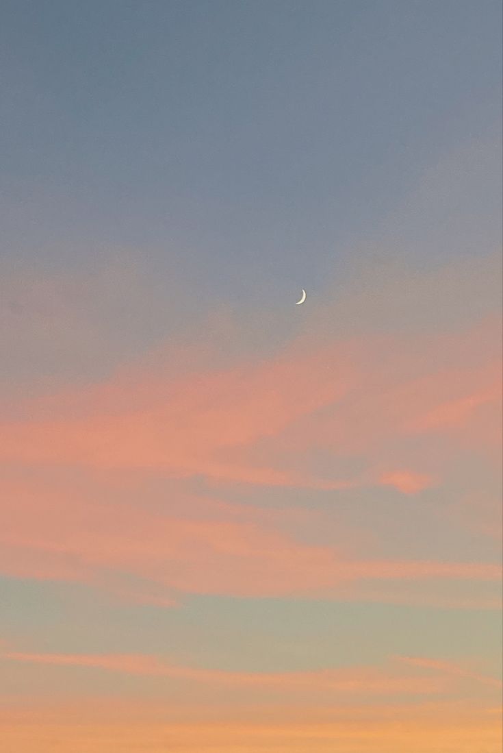 the sky is pink and blue as the sun sets in the distance with an airplane flying overhead