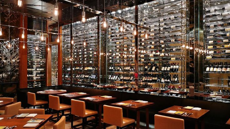 an empty restaurant with lots of bottles on the wall and tables in front of it