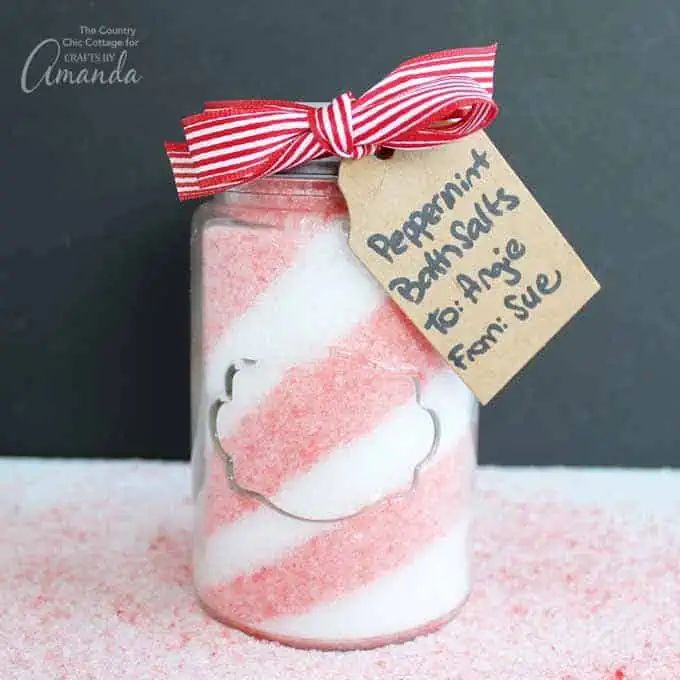 a jar filled with pink and white sugar next to a tag that says peppermint bath salts for more fun