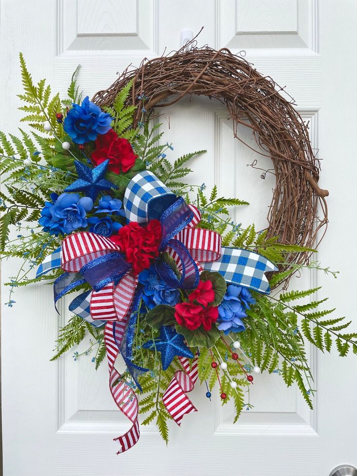 a wreath with red, white and blue flowers is hanging on the front door to show patriotic colors