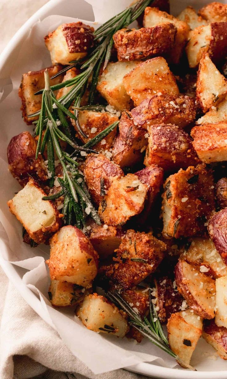 a white bowl filled with cooked potatoes and herbs