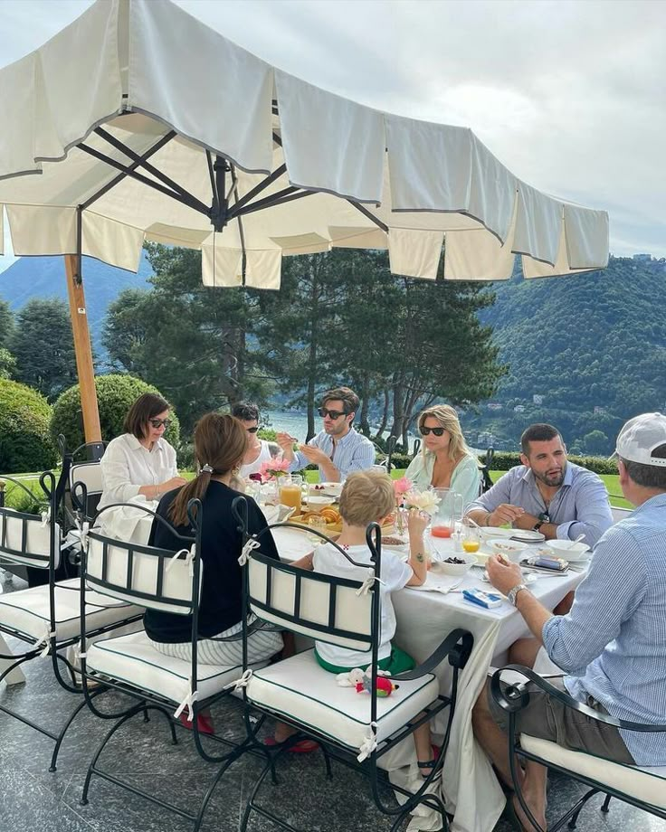 a group of people sitting around a table under an umbrella