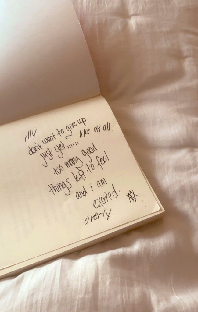 an open book sitting on top of a bed with writing on the pages in cursive handwriting