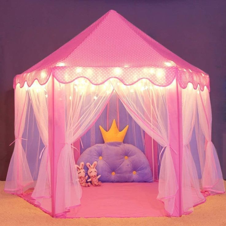 a pink tent with lights on it and stuffed animals in the bed area under it