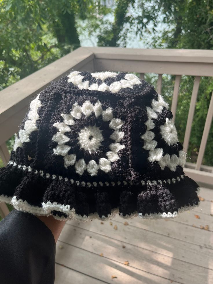 a person wearing a black and white crocheted hat on top of a wooden deck