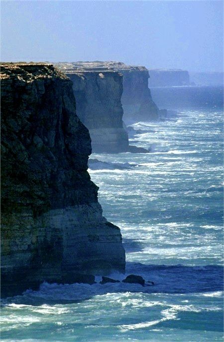 an ocean cliff with waves crashing against it