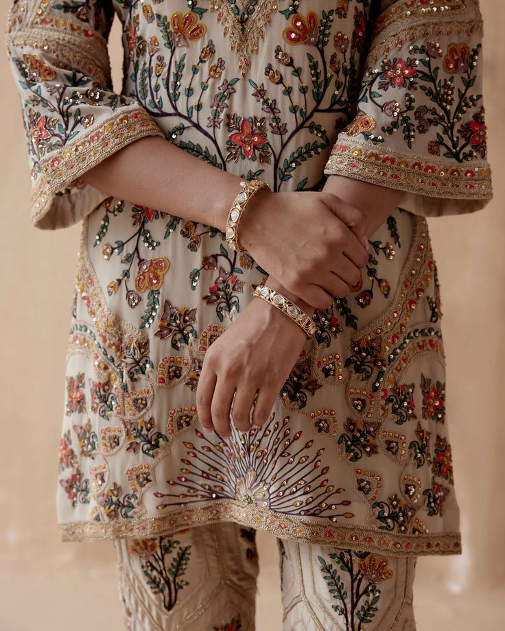 Editor's Note Introducing an elegant ivory kurta adorned with intricate floral thread embroidery, beautifully highlighted with various embellishments. This exquisite piece is paired with pants, creating a graceful and sophisticated ensemble perfect for special occasions or cultural events. The delicate embroidery and thoughtful embellishments add a touch of charm, making this outfit a stunning choice for those who appreciate timeless beauty and style. Fabric: Pure georgette Color: Ivory Componen Floral Thread Embroidery, Kurta And Pants, Embroidery Kurta, Delicate Embroidery, Embroidered Pants, Cultural Events, Charm Making, Thread Embroidery, Embroidery Suits