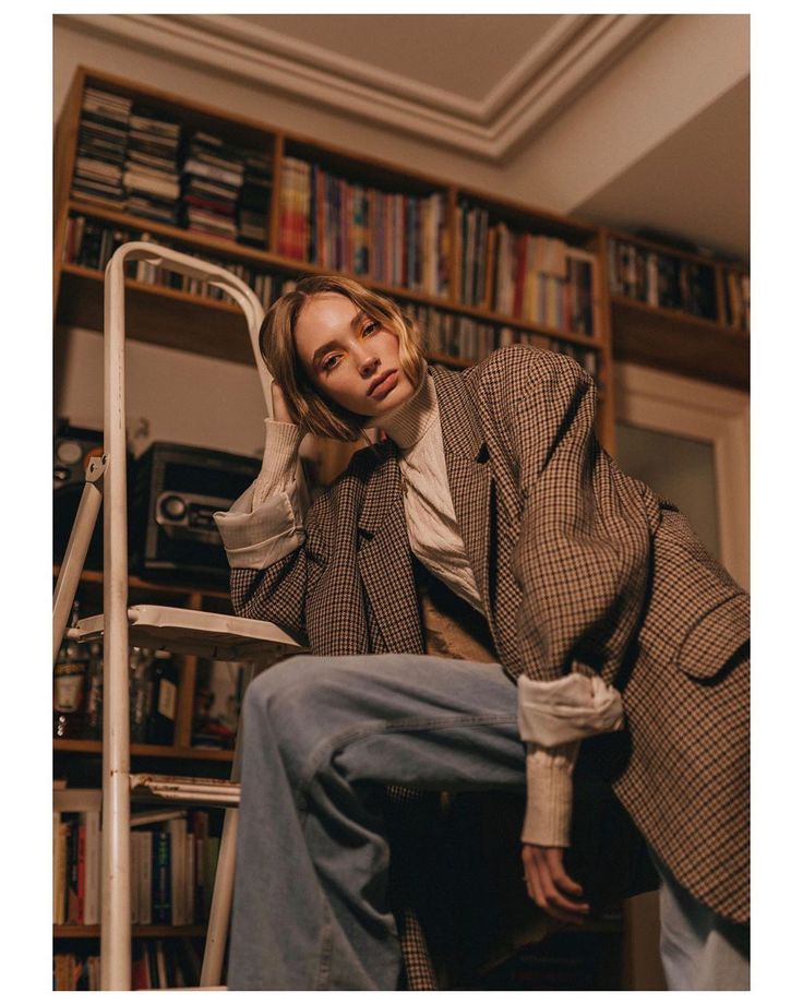 a man sitting on top of a chair next to a book shelf