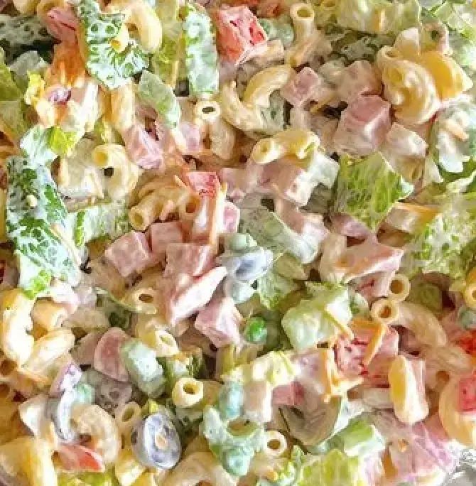 pasta salad with ham and broccoli is shown in a bowl, ready to be eaten