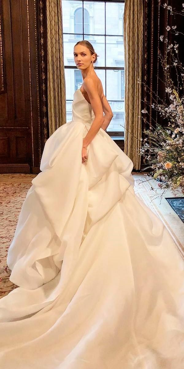 a woman in a white wedding dress standing by a window