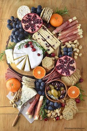 an assortment of cheeses, fruits and meats arranged in a circle on a wooden table