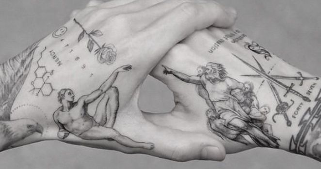 two hands holding each other with tattoos on them