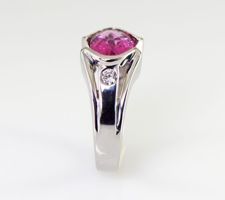 A dazzling pink Tourmaline checkerboard cut from Brazil is is accented with two flush set diamonds in this gorgeous 14k white gold ring. The natural Tourmaline is a 9 x 7 mm oval shape checkerboard cut and weighs 1.93 carats. The two diamonds are round brilliant cuts measuring 2.8mm with a total weight of .16 carats G-H color VS1-2 clarity The ring is 10.5 mm wide (3/8 inch) at the stone tapering down to 3.5 mm The height of the ring is 6 mm Ring weighs 7.31 grams Size 6 3/4 All items from Stowe Pink Platinum Ruby Ring For Wedding, Formal Pink Sapphire Ring In Platinum, Pink Platinum Diamond Ring For Anniversary, Pink Sapphire Ring In Platinum For Anniversary, Pink Sapphire Platinum Ring For Anniversary, Pink Diamond Formal Birthstone Ring, Pink Round Cut Birthstone Ring For Formal Occasions, Pink Diamond Birthstone Ring For Formal Events, Pink Diamond Birthstone Ring For Formal Occasions