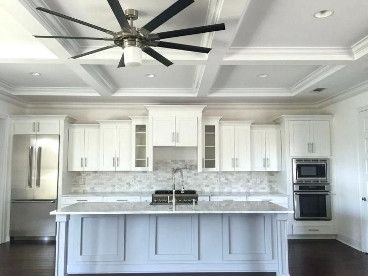 a large kitchen with white cabinets and black ceiling fans in it's center island