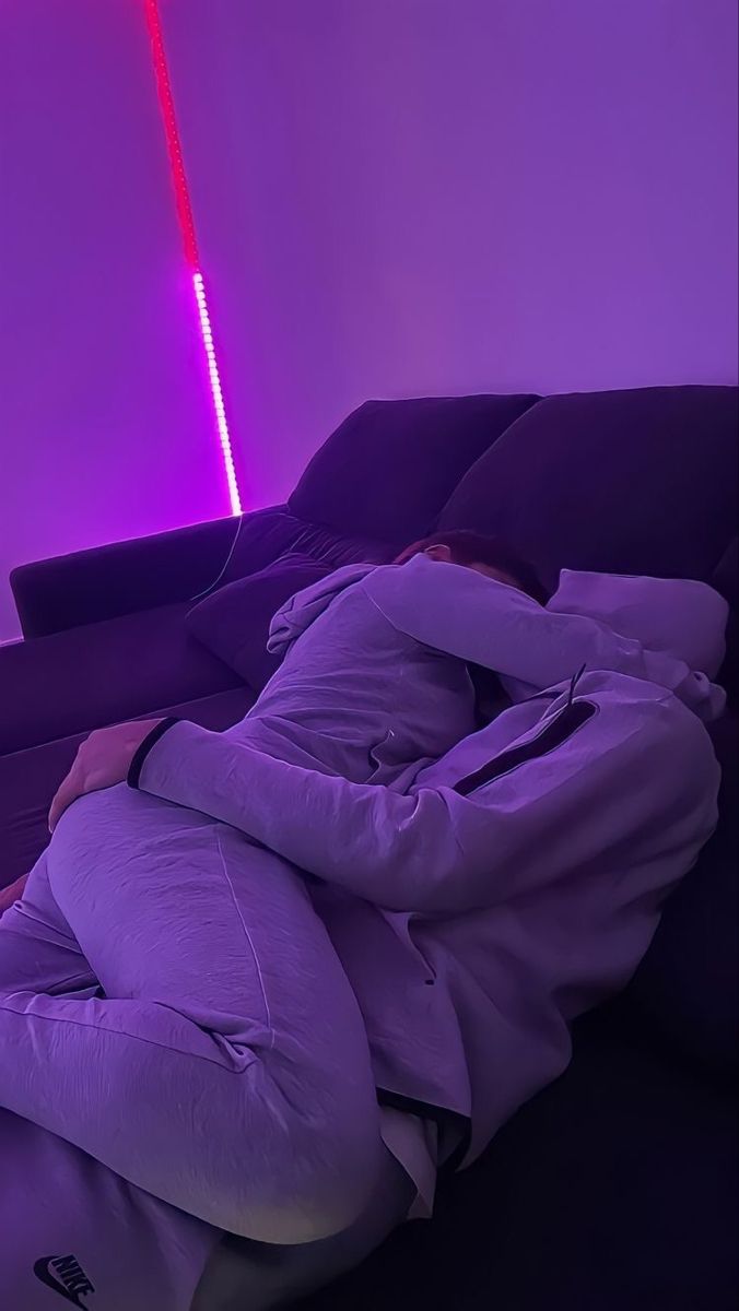 a man laying on top of a couch under a purple light