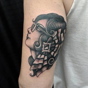 a woman's arm with a black and white tattoo design on her left arm