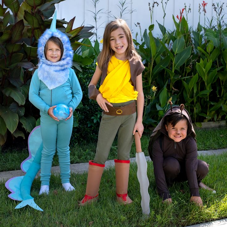 three girls dressed up as pokemon and toothbrushes in front of some bushes with plants