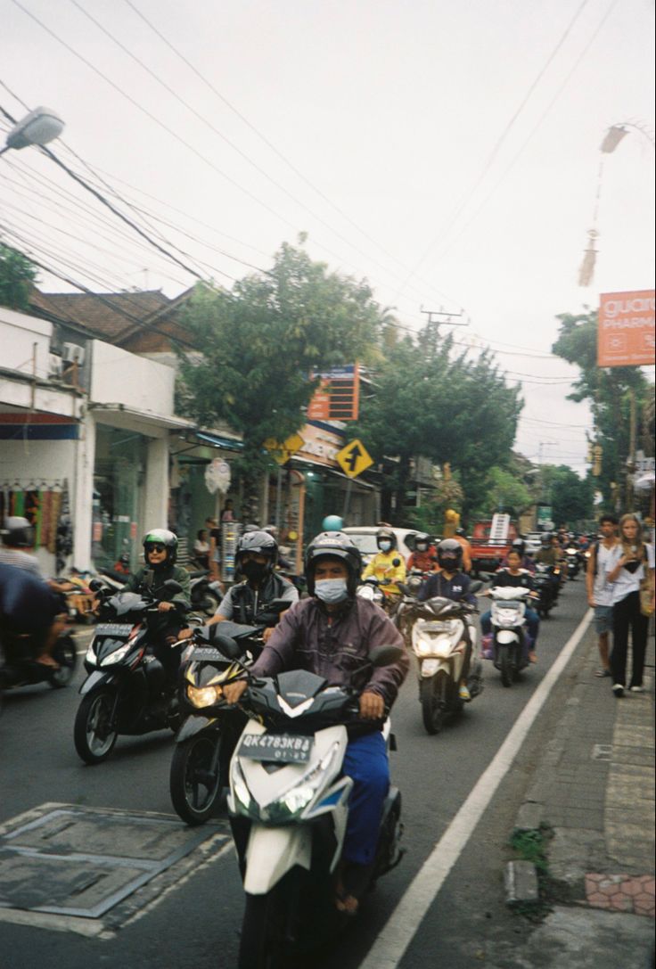 motorcyclists are riding down the street on their bikes and scooters