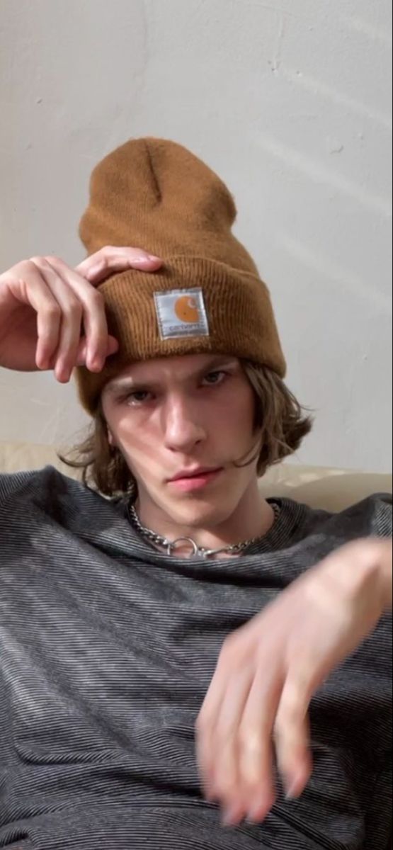 a young man wearing a beanie sitting on top of a couch