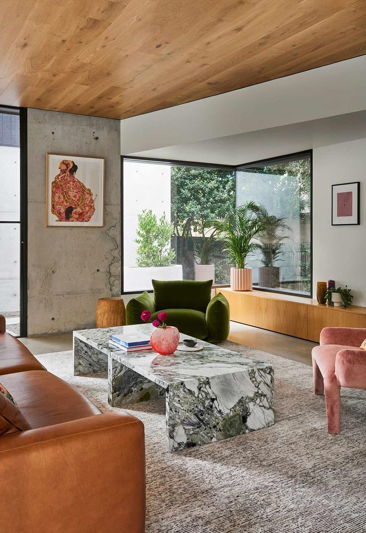 a living room with couches, chairs and tables in front of large windows that look out onto the outdoors