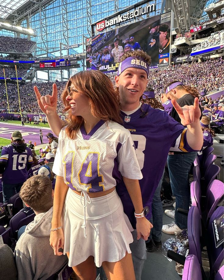 a man and woman standing next to each other at a football game