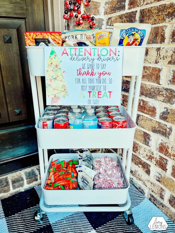 a white cart filled with candy sits in front of a brick wall and has a sign on it