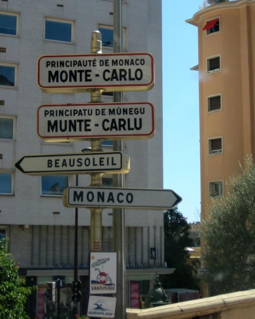 several street signs on a pole in front of a tall building with windows and balconies