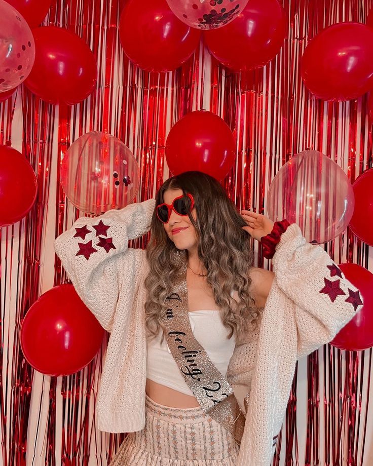 a woman standing in front of balloons and streamers with her hands on her head