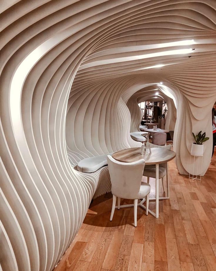 the interior of a modern restaurant with curved walls and wooden floors, white chairs and tables