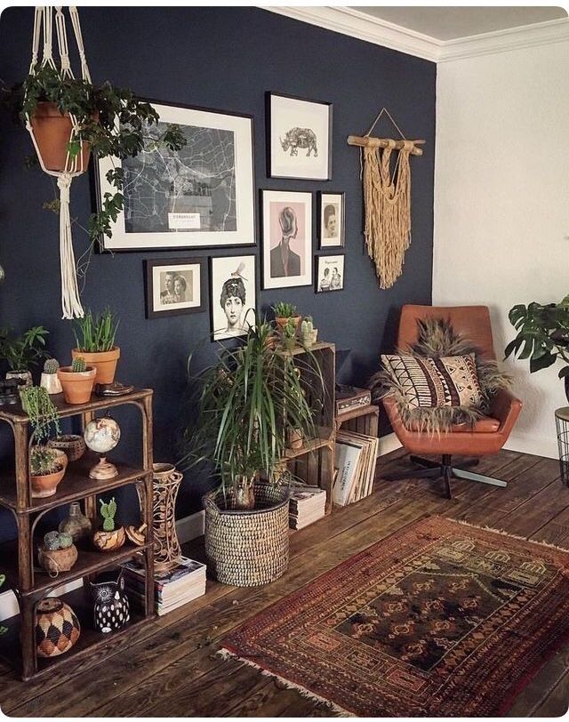 a living room filled with plants and pictures on the wall