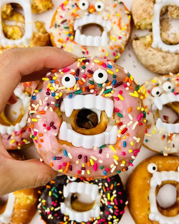 a person holding a doughnut with sprinkles and eyes