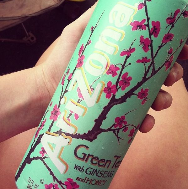 a person holding up a can of green tea with pink flowers on the top and bottom