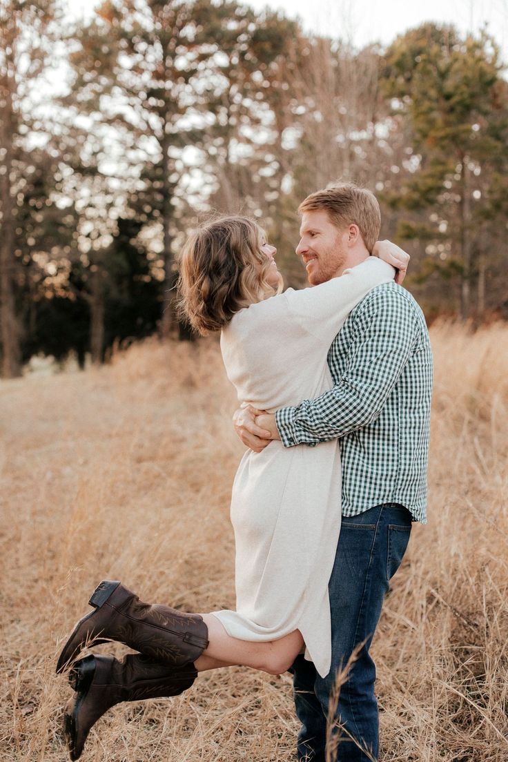 a man and woman hugging in the middle of tall grass with trees in the background