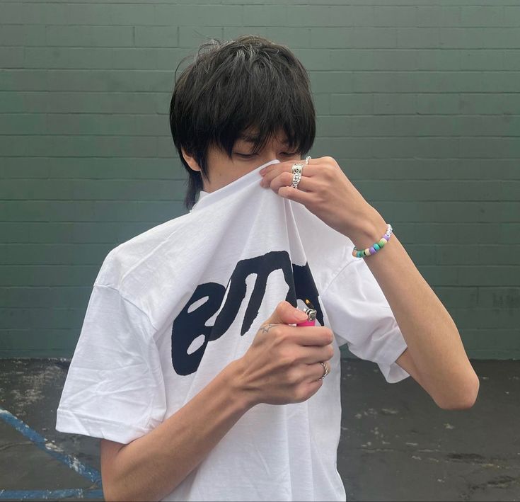 a young man covers his face with a t - shirt