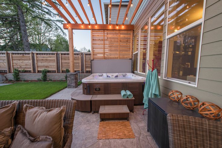 an outdoor hot tub in the middle of a patio with seating and lights above it