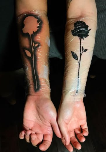 two people with tattoos on their arms holding each other's hands and one has a rose tattooed on it