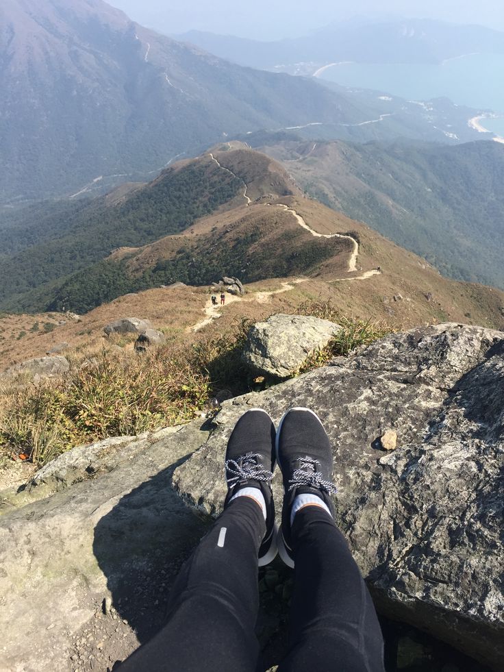 someone is sitting on top of a mountain with their feet up and looking at the view