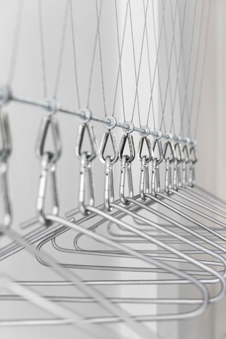 several metal clothes hangers are hanging in a row on the wall, with hooks attached to them