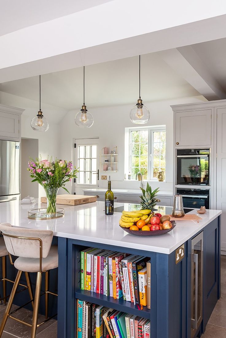 a kitchen with an island, bookshelf and two stools in front of it