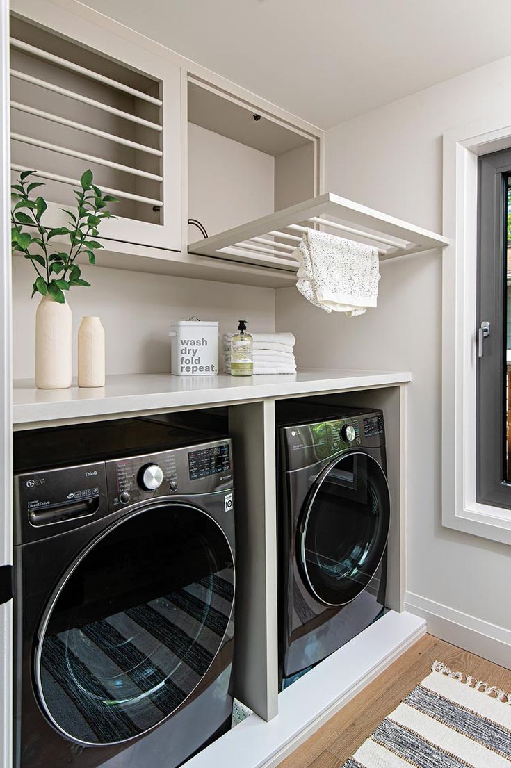 a washer and dryer in a small room next to a window with shutters