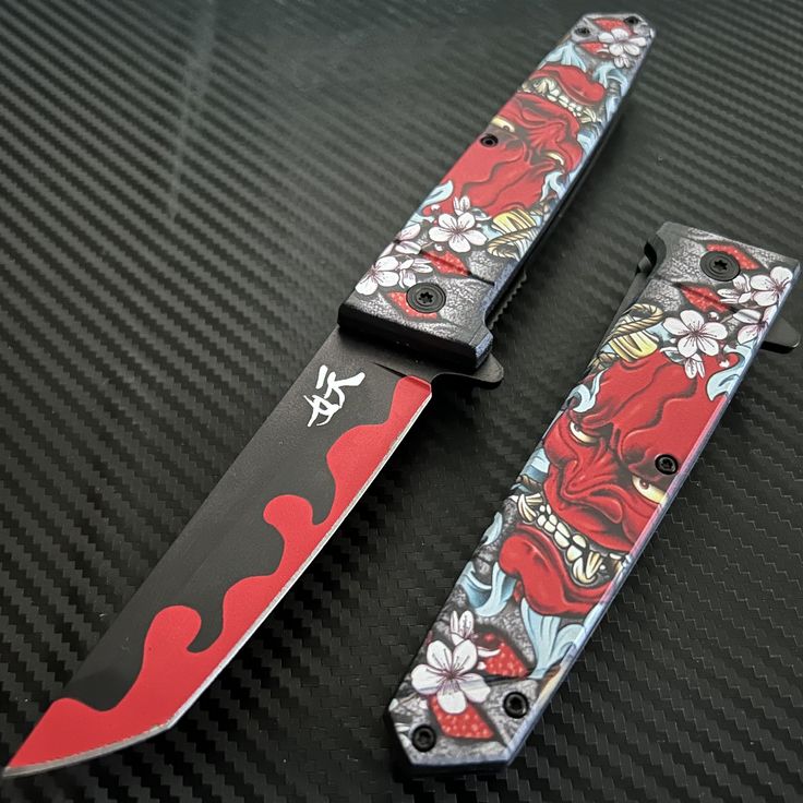 two knifes with designs on them sitting on a black table next to each other