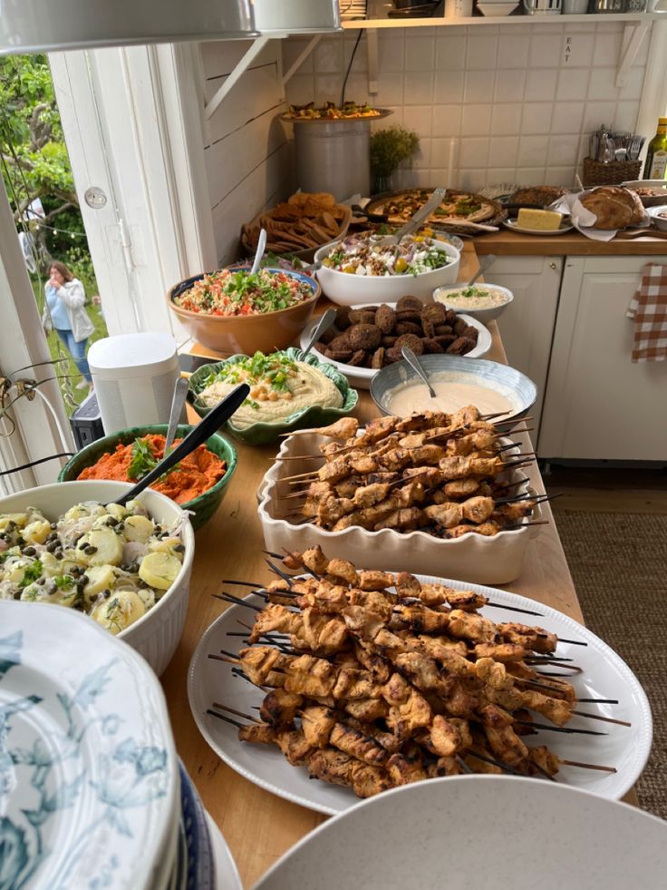 a table filled with lots of different types of food on skewers and plates