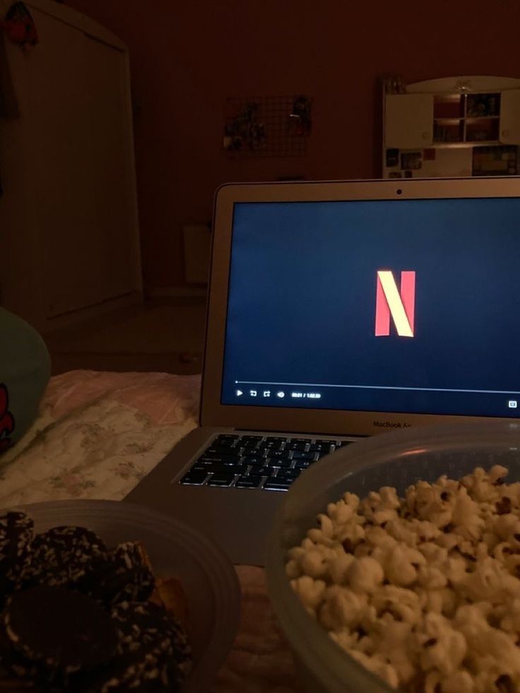 an open laptop computer sitting on top of a table next to a bowl of food