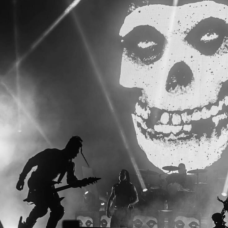 a group of people standing on top of a stage next to a giant skull head