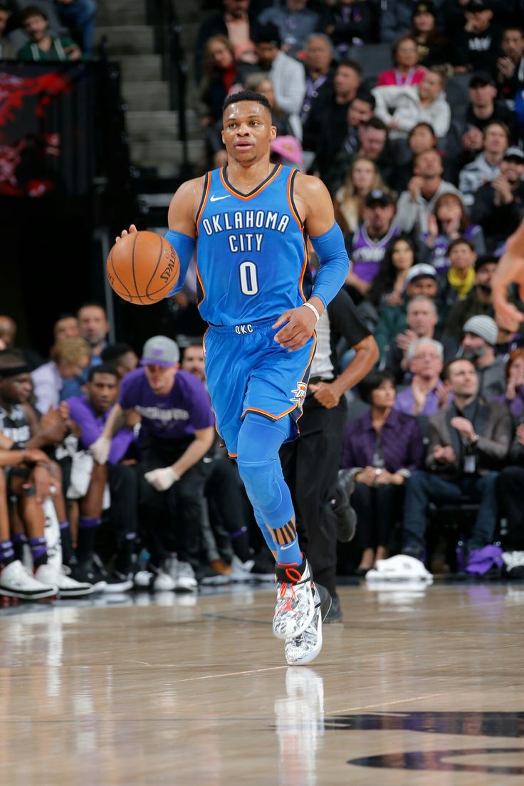 a basketball player dribbling the ball down the court while people watch from the stands