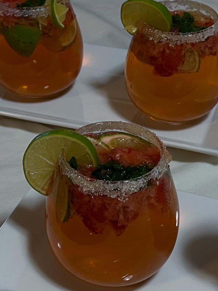 three glasses filled with drinks and garnished with limes