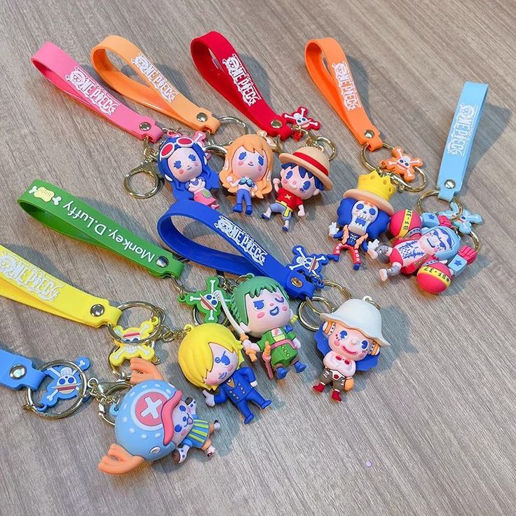 several key chains with cartoon characters are on the floor next to each other and one is holding a cell phone